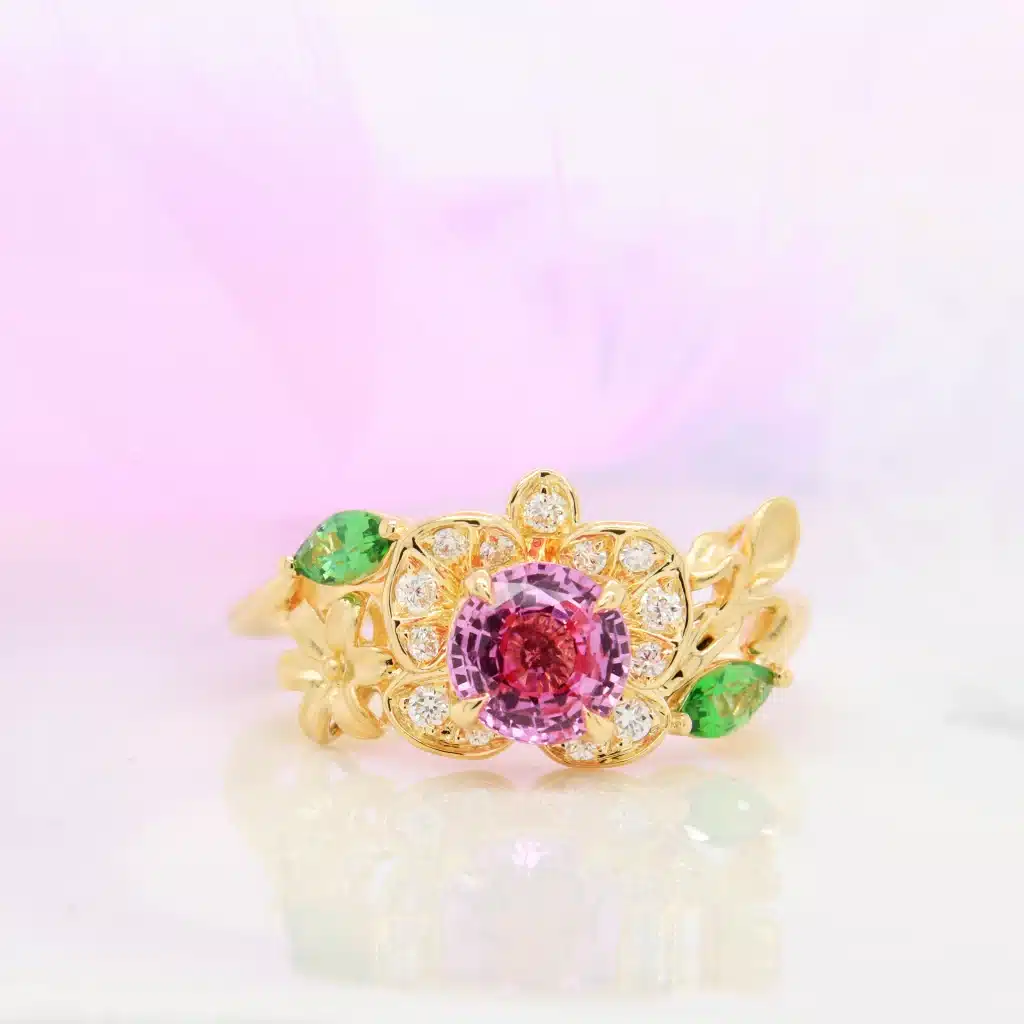 Bespoke floral ring with vivid pink unheated sapphire, orchid design, lily and jasmine side motifs representing Singapore, Philippines, and Italy.